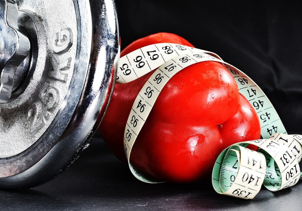 One end of a dumbbell, some red peppers and a tape measure