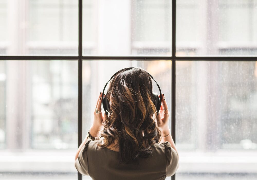 A woman wearing headphones looking out of a window