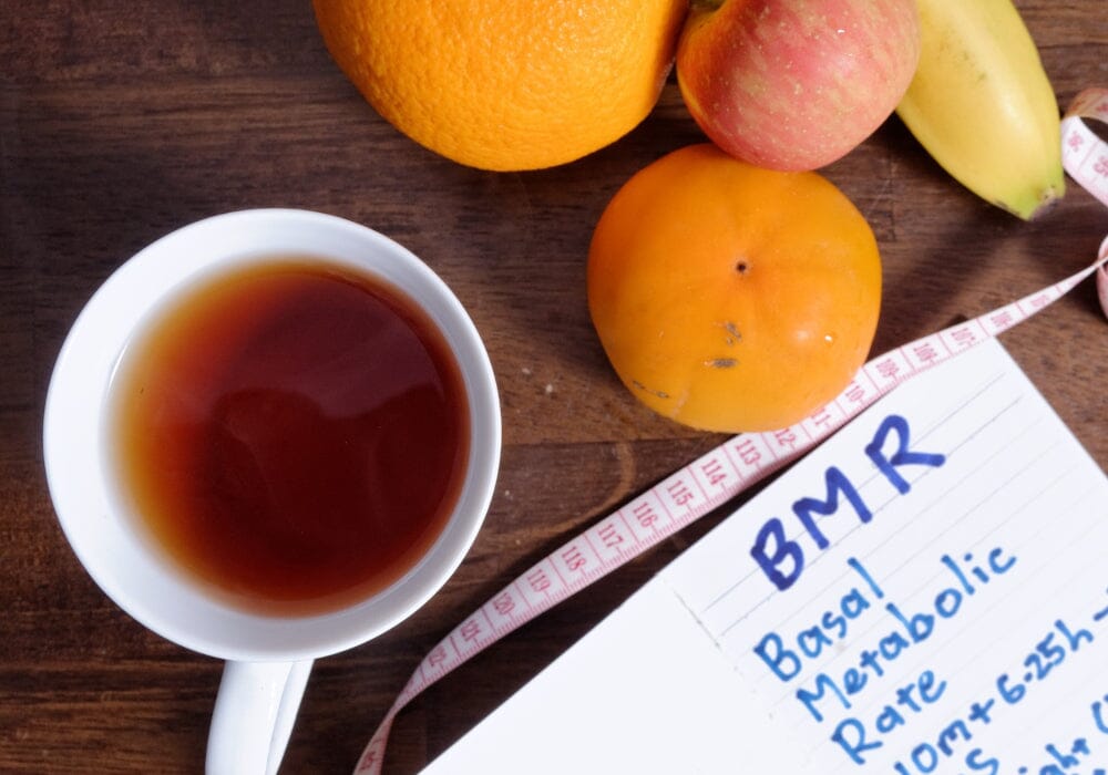 A cup of tea, some fruit, a tape measure and a notebook that says basal metabolic rate