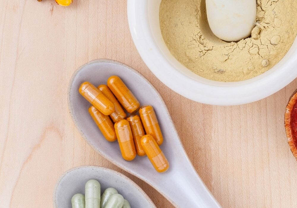 Capsules on a spoon and powder in a pestle and mortar