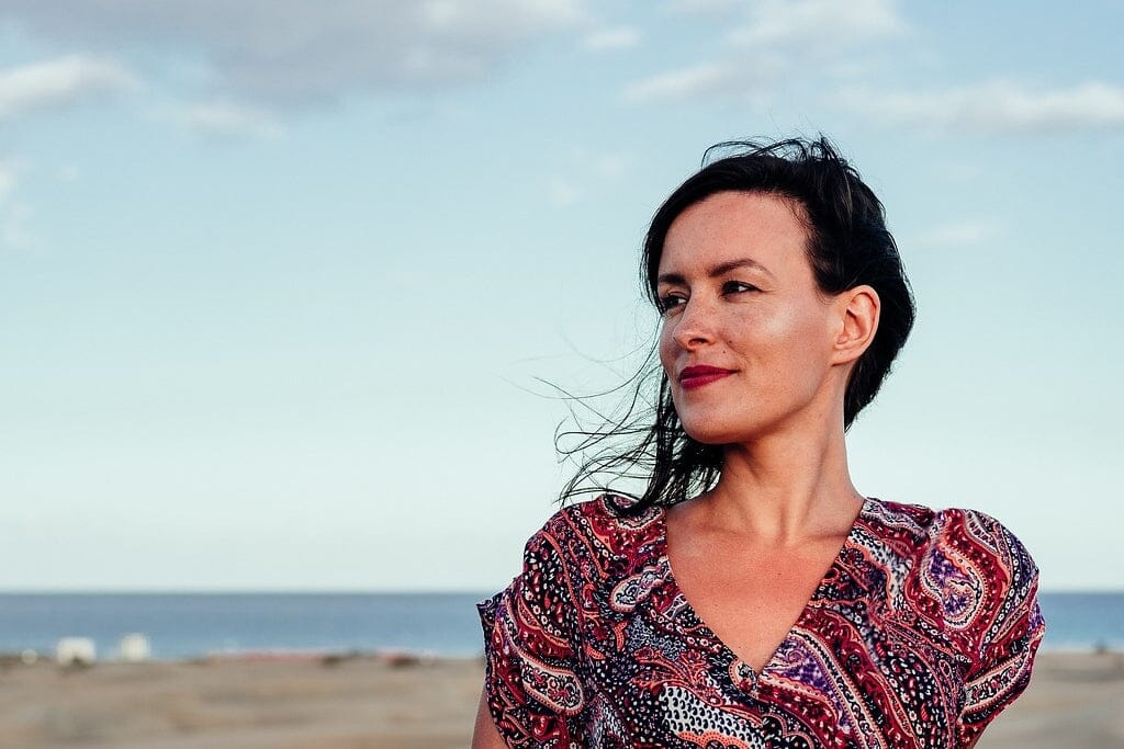 A woman's head and shoulders with background of beach and sea