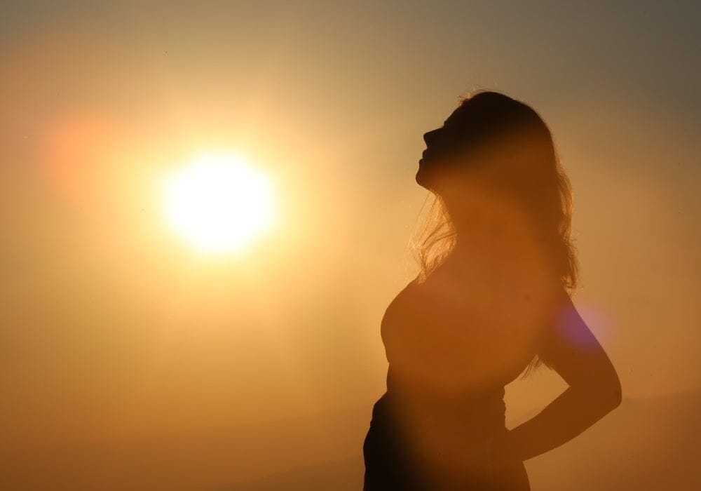 A woman silhouetted against the sun